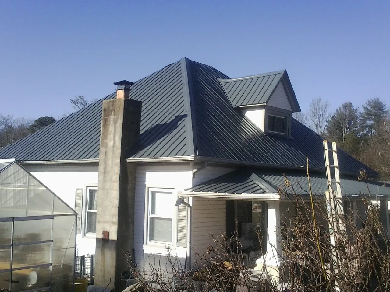 Dark blue standing seam metal roof on a white farmhouse with dormer — Slate & Tile Roof Repair by Roofing Brothers in Mahanoy City