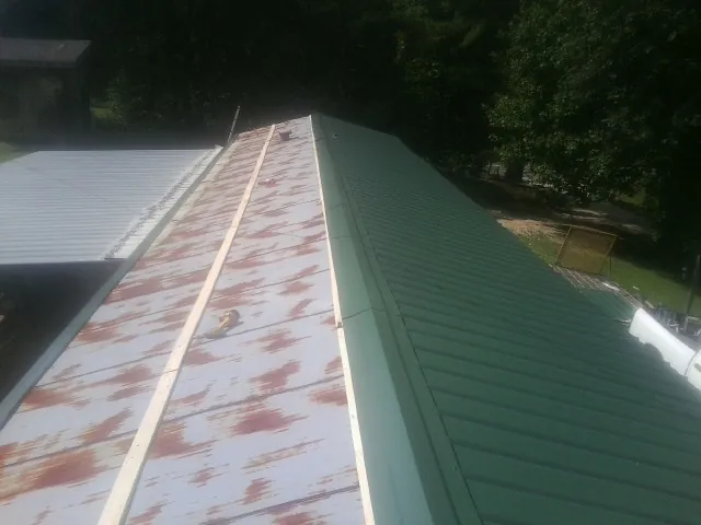 Old rusted panels beside newly installed green metal roofing — Wind Damage Roof Repair by Roofing Brothers in Mahanoy City