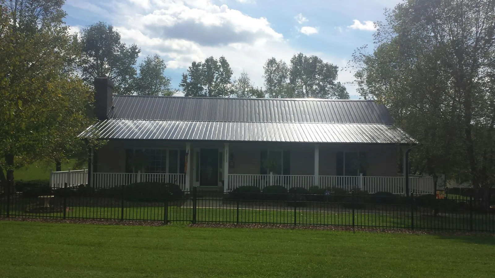 Gray metal roof on a brick ranch with a full width front porch — Gutter Guard Installation work by our crew in Mahanoy City
