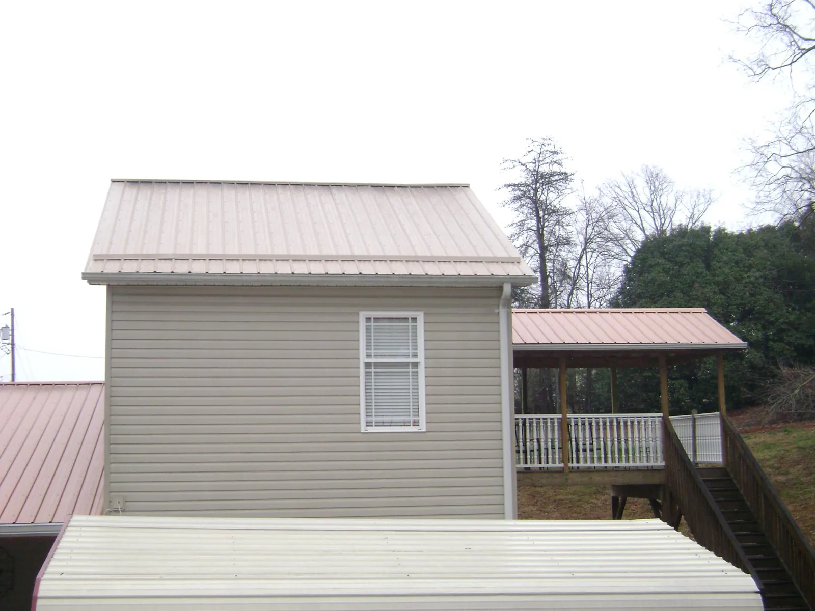 Tan metal roofs on a two story addition and attached porch, from a Roof Replacement job in Mahanoy City