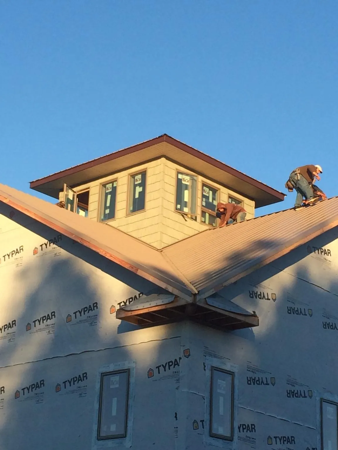 Roofers working around a rooftop cupola on a new metal roof at sunset — Roof Waterproofing in Mahanoy City by Roofing Brothers